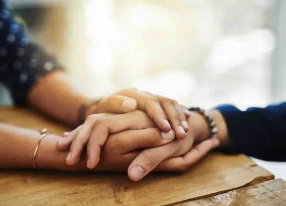 Deux personnes se tenant la main en signe de soutien et de condoléances.